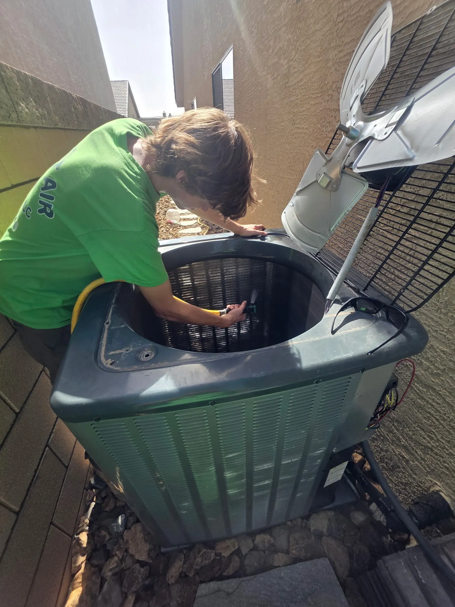 Comfort Air Solutions technician servicing the top of an outdoor condenser