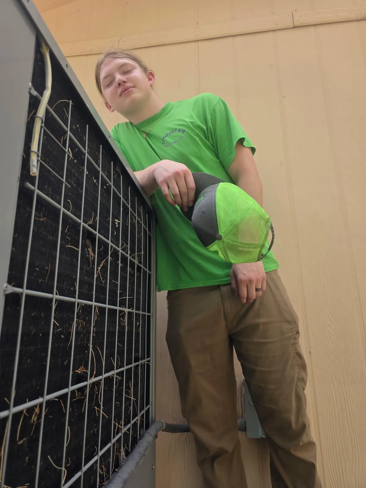 Comfort Air Solutions technician beside an outdoor unit on a job