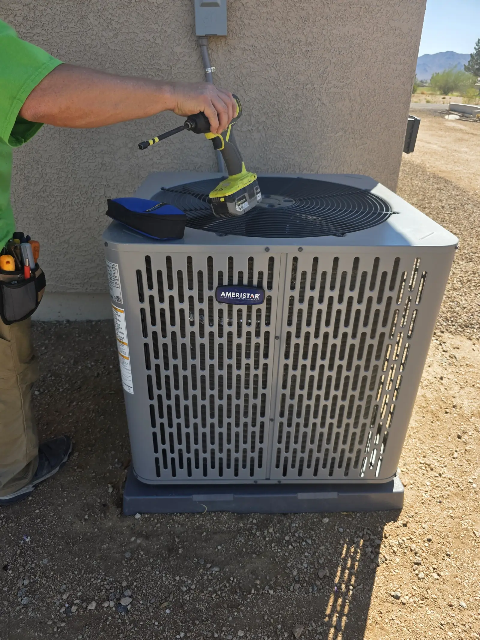 Comfort Air Solutions technician working at the top of a residential condenser