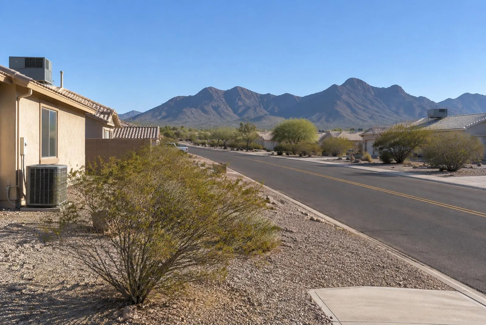 A residential street with desert yards and AC condensers in Golden Valley