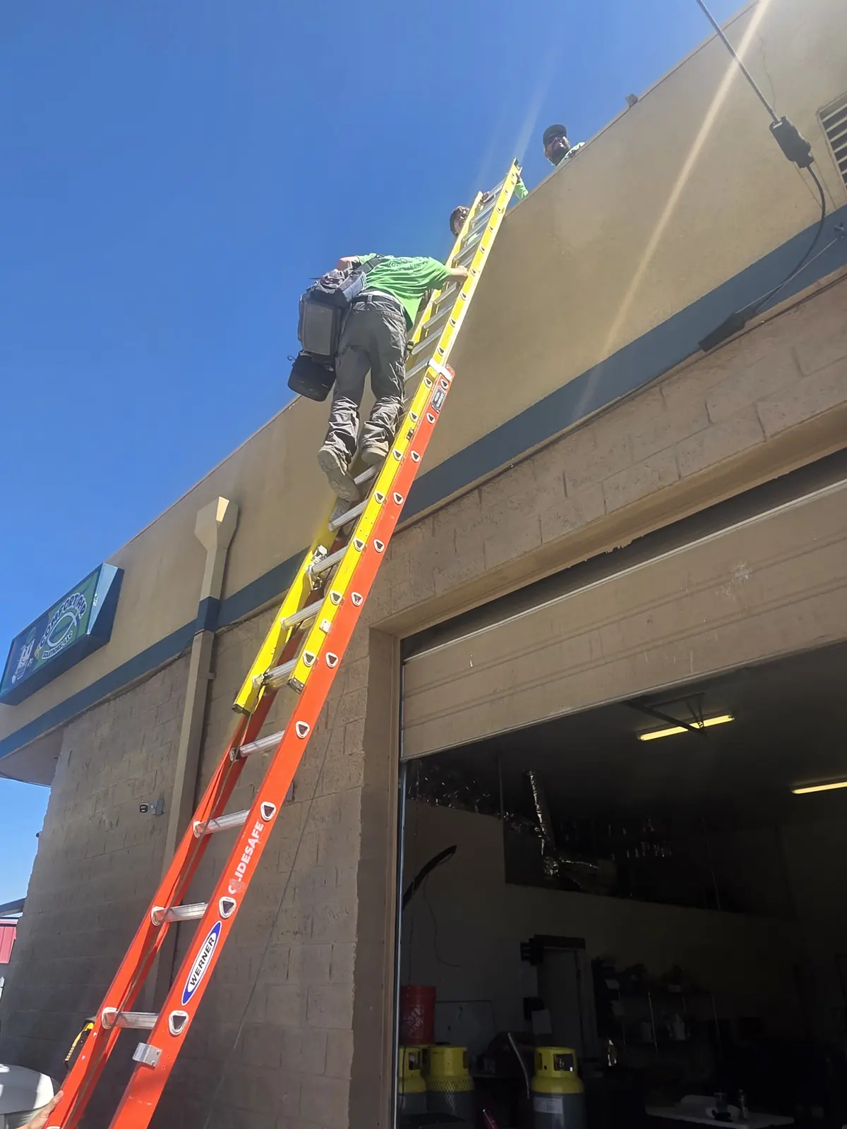 Comfort Air Solutions technicians climbing a ladder to the shop roof