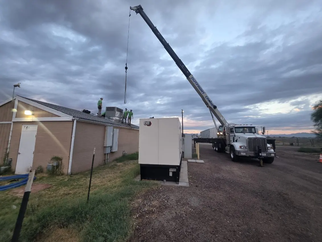 Crane positioned beside a building while the Comfort Air Solutions crew works on the roof
