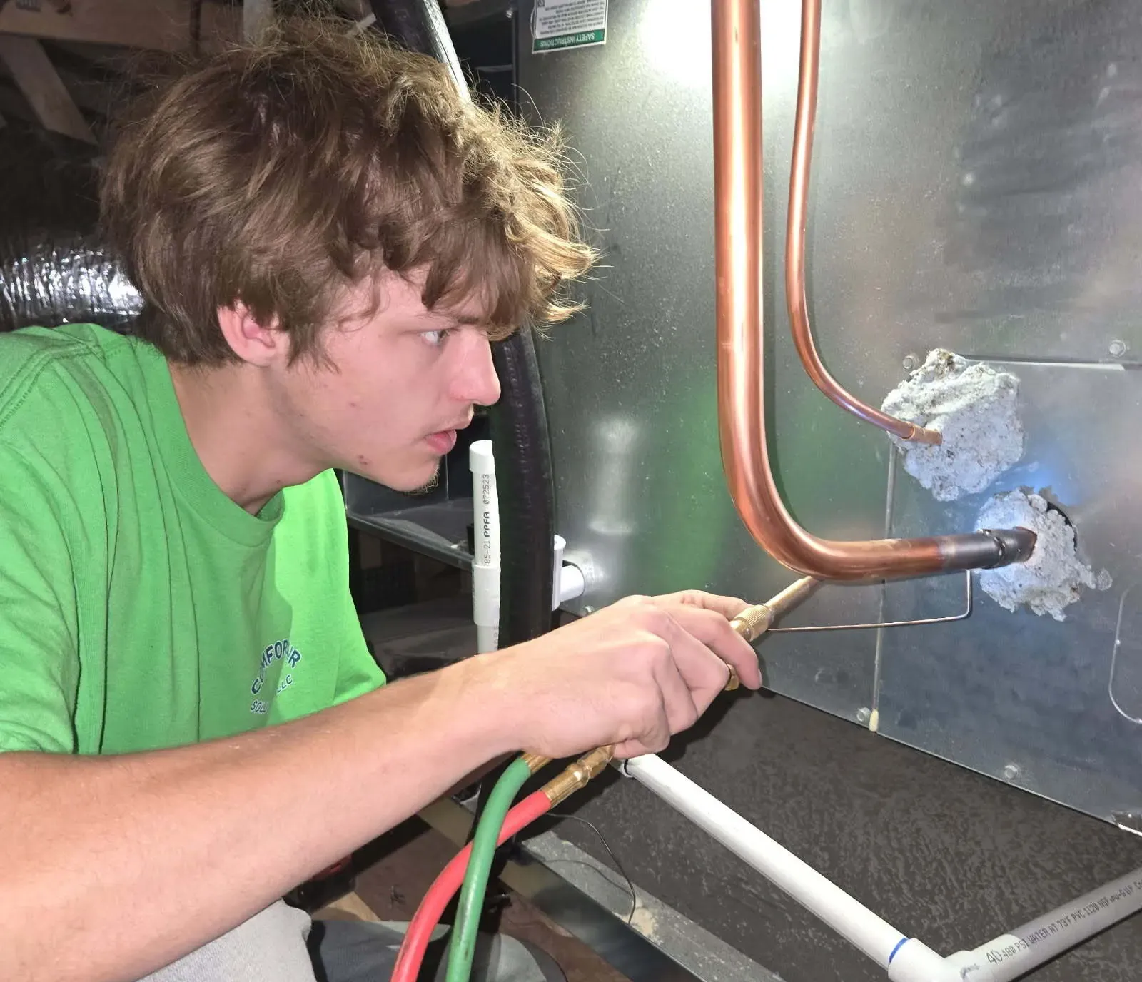 Technician brazing refrigerant line at a new air handler