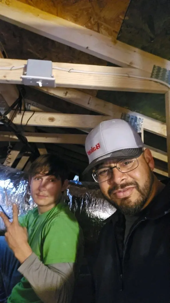 CAS technicians beside an attic air handler during a maintenance visit