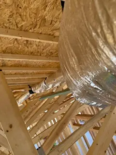 Insulated duct runs routed through roof trusses on a new construction job
