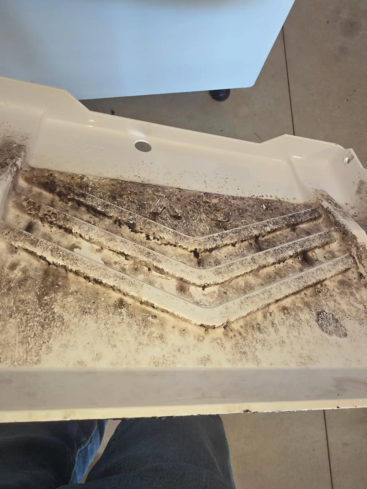 Before cleaning: soiled water tray inside an ice machine