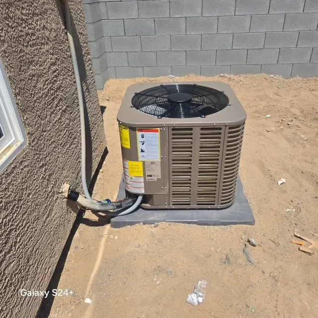 Newly installed outdoor condensing unit set on a pad beside a home