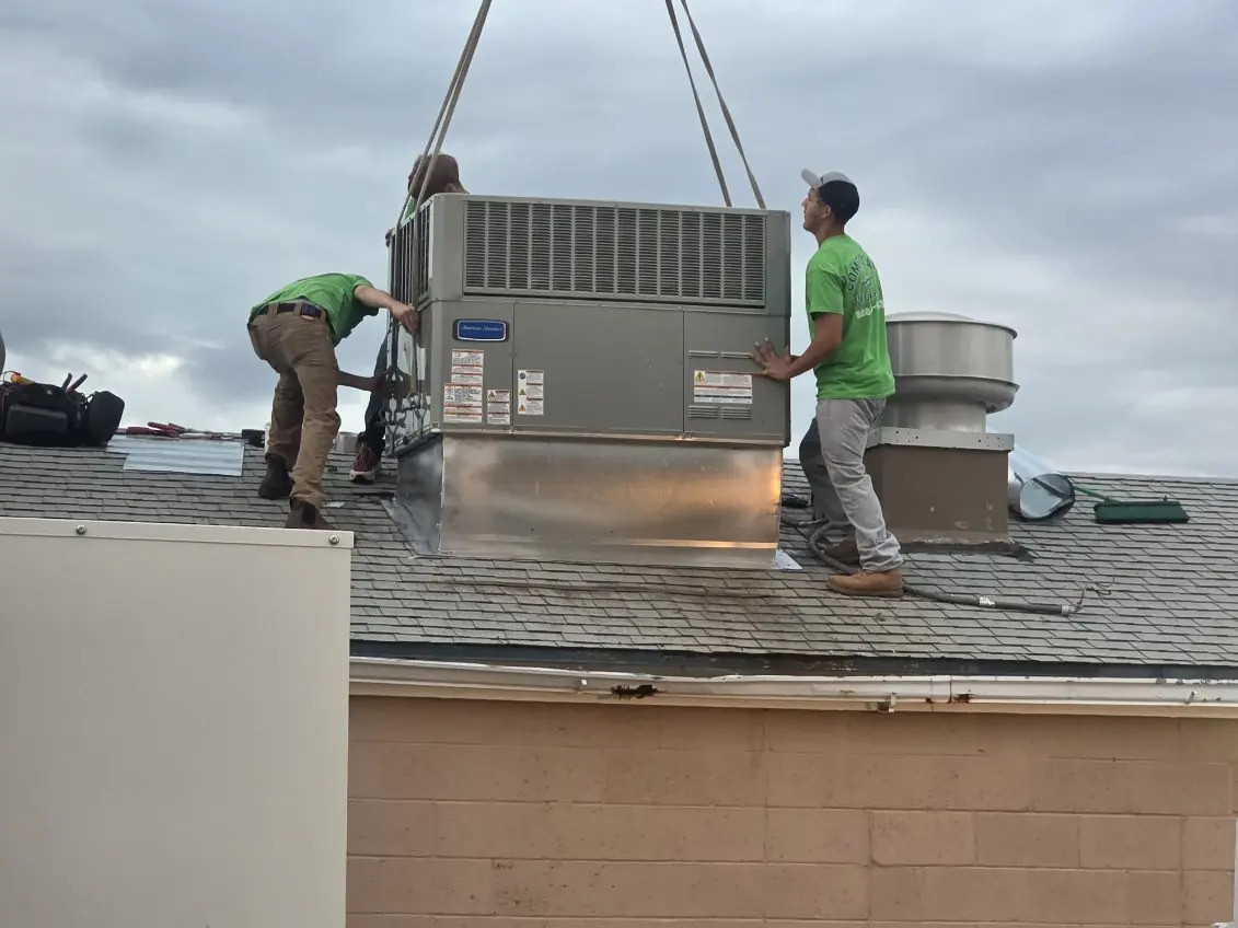 Crane setting commercial HVAC equipment on a roof