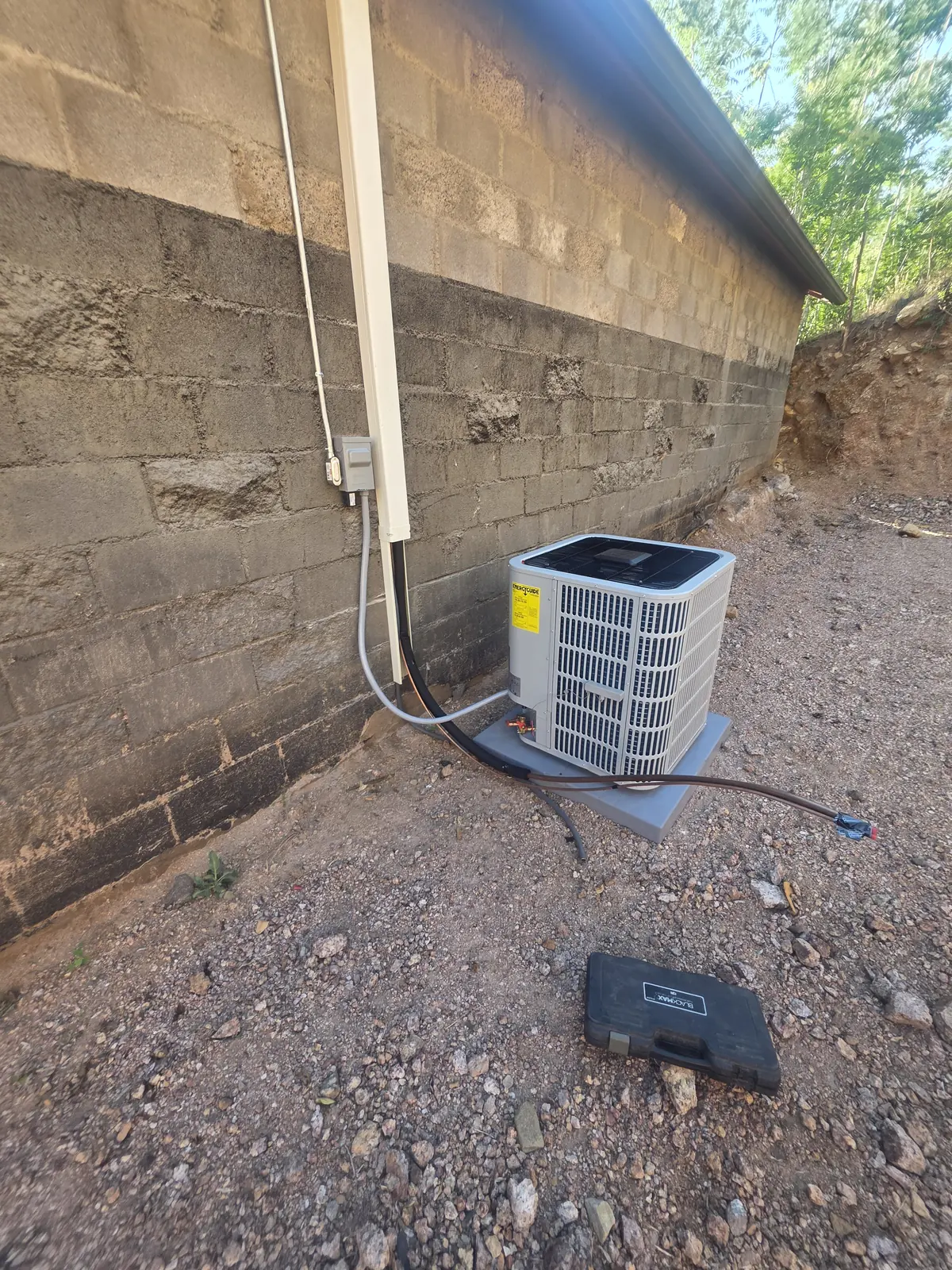 Technician servicing the top of an outdoor AC condensing unit
