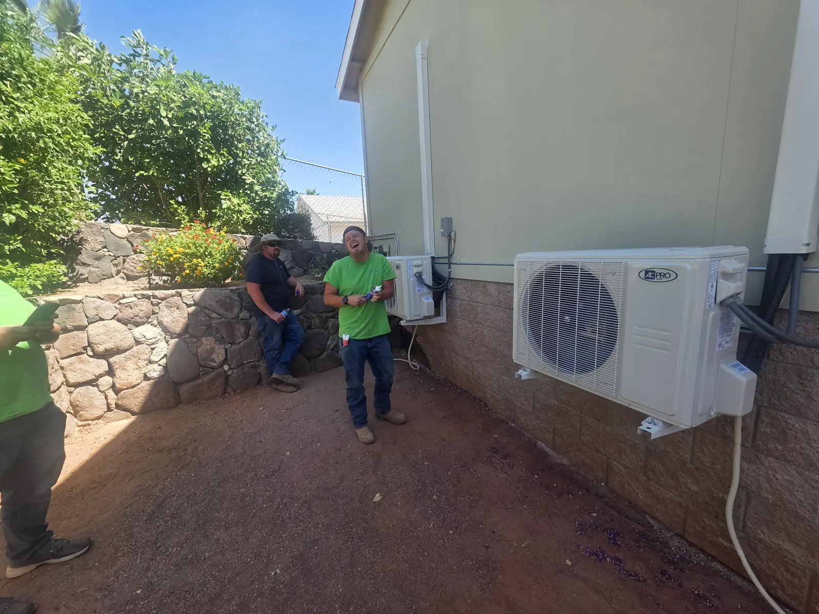 Comfort Air Solutions crew installing a ductless outdoor unit beside a home