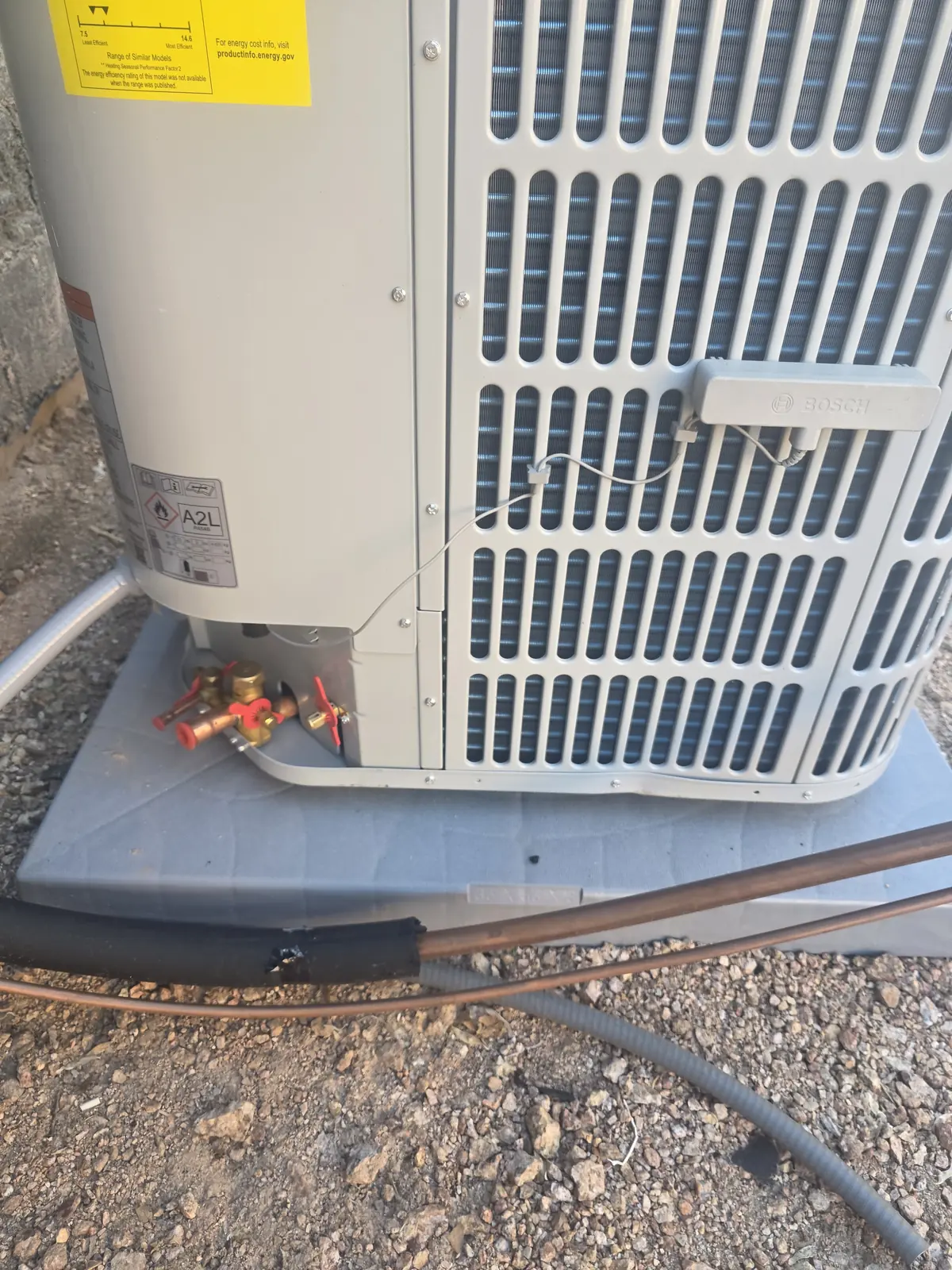 Technician servicing the top of an outdoor heat pump or condensing unit during heating service