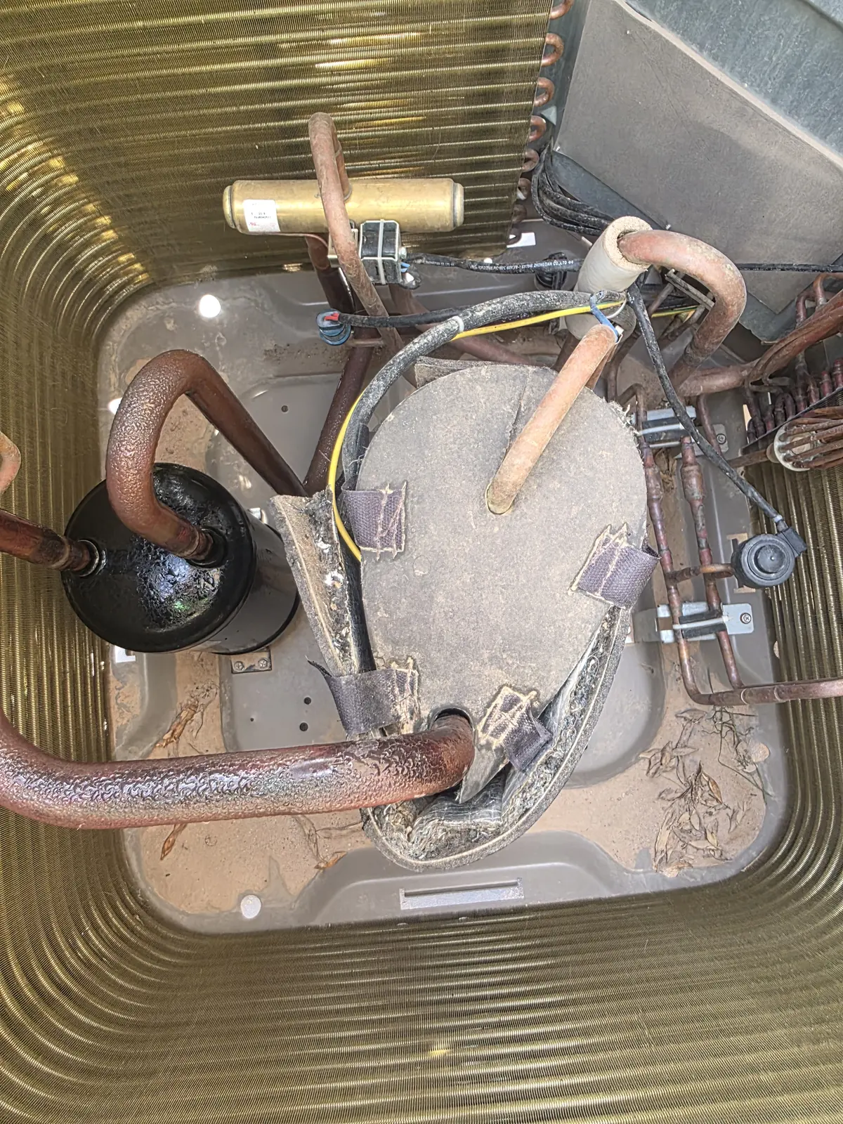 Inside an outdoor condensing unit, showing the compressor and refrigerant piping