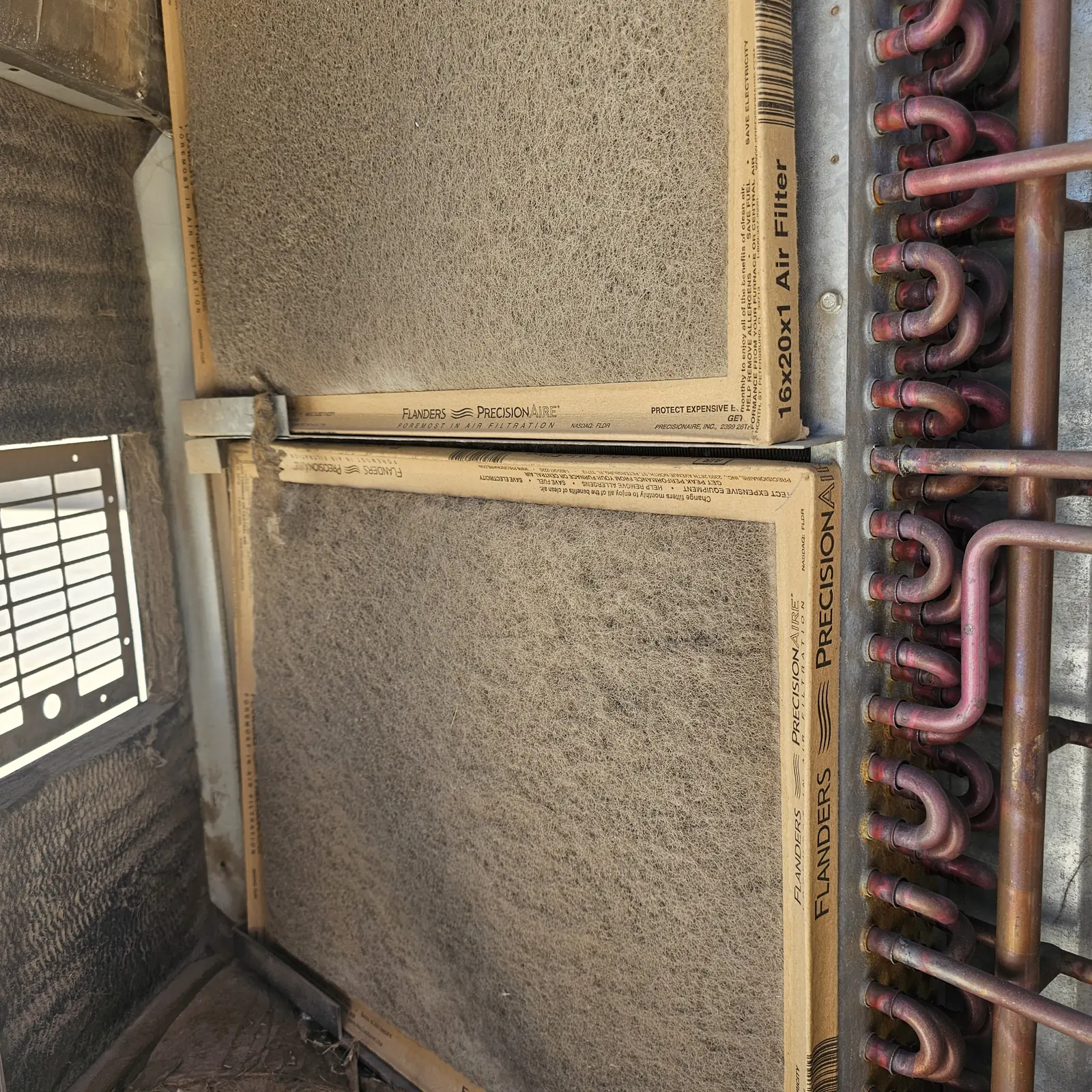 Dust-covered filters beside a coil inside an air handler