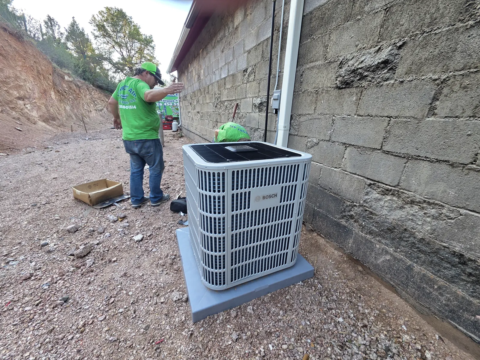CAS technician working at an outdoor unit on a hillside home